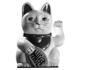 A black-and-white maneki-neko, the Japanese beckoning cat, raising one paw for luck.